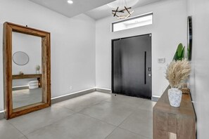 A modern interior with a large mirror, a black door, and a wooden console with a vase. - The signature Luxury Las Vegas Getaway (Las Vegas)