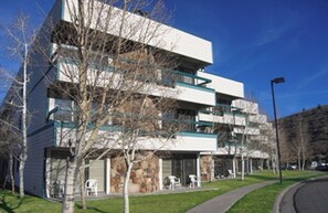 A multi-story building with a flat roof, balconies, and a parking area with a few cars. - Christmas in Park City Ski Condo, slps 6, full kitchen, ski shuttle, Dec. 19-26 (Park City)