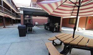 An outdoor patio area with a grill, tables, and a trash bin. - Christmas in Park City Ski Condo, slps 6, full kitchen, ski shuttle, Dec. 19-26 (Park City)