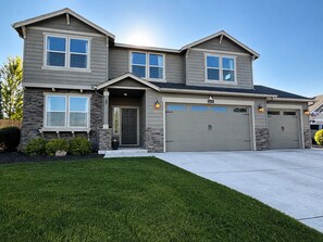 A two-story house with a garage, stone accents, and a well-maintained lawn.
