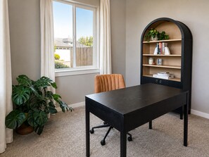 Une pièce comprenant un bureau, une chaise, une bibliothèque et des plantes en pot.
