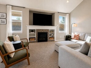 A living room with a fireplace, a television mounted above it, and a sofa.