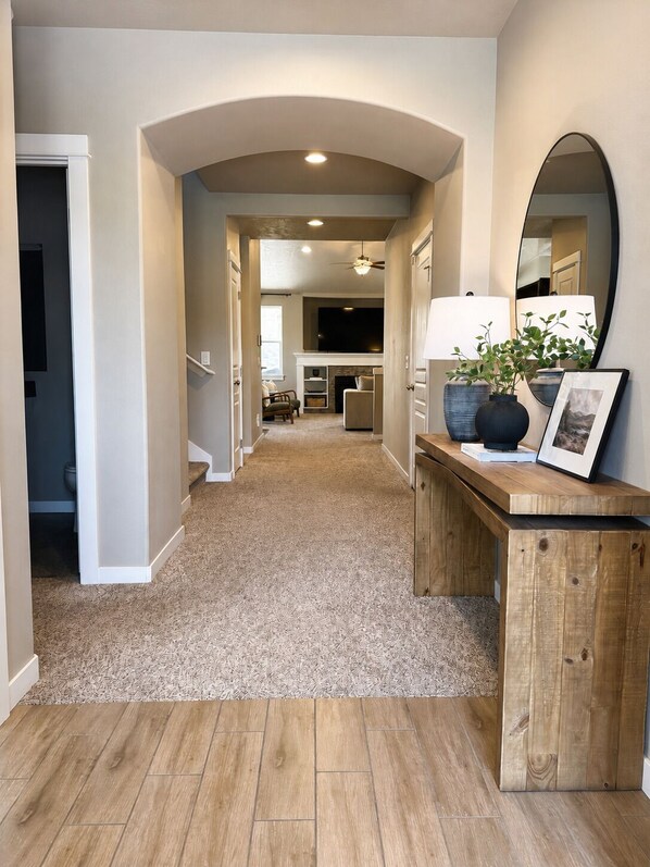 A hallway with a wooden floor, a fireplace, a television, and a mirror.