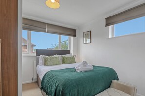 A bedroom with a bed, a window, a radiator, and a wall-mounted picture.