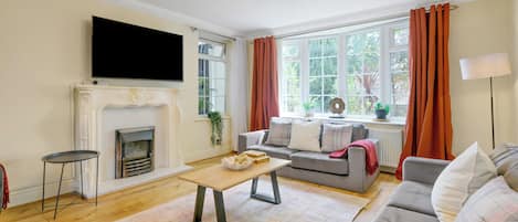 A living room with a fireplace, sofa, television, and a view of the outdoors.
