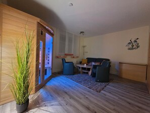 A modern living room with a wooden floor, a blue sofa, a small table, and a potted plant.