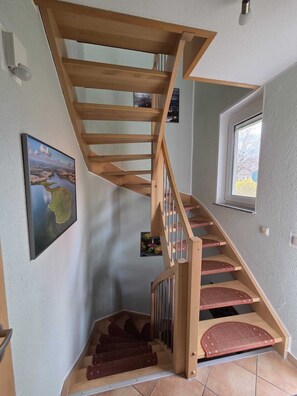 Eine Wendeltreppe aus Holz mit roten Teppichstufen, die zu einer oberen Etage führen.