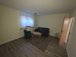 Ein Wohnzimmer mit Sofa, Sessel, Couchtisch und Heizkörper.
