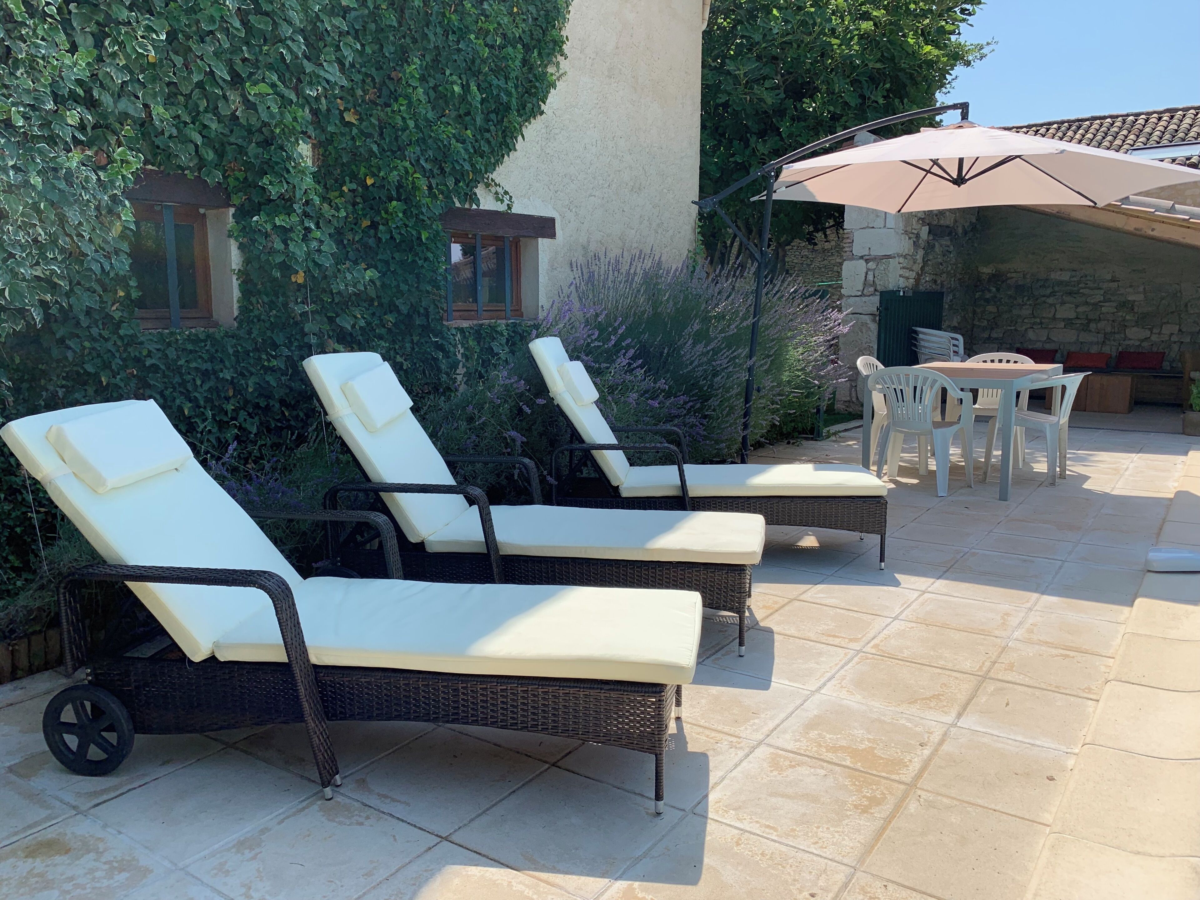Een terras met rieten lounge fauteuils, een tafel en een parasol.