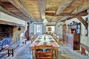 A rustic dining room with a long wooden table set for a meal, flanked by wooden benches and a stone fireplace. - Authentic, renovated 3-bedroom house in the Périgord region (Plaisance)