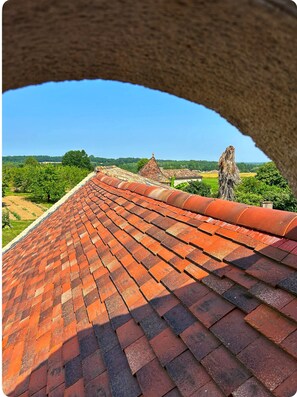 A red-tiled roof with a view of a green landscape and a distant building. - Authentic, renovated 3-bedroom house in the Périgord region (Plaisance)