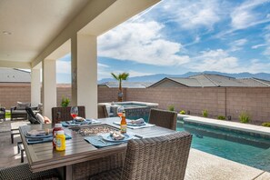An outdoor dining area with a pool, wicker furniture, and a clear view of the mountains. - Grill and Chill by J and Amy BL 992912 (Mesquite)
