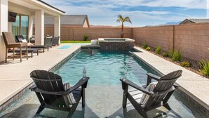 A swimming pool with lounge chairs, a hot tub, and a view of the mountains. - Grill and Chill by J and Amy BL 992912 (Mesquite)