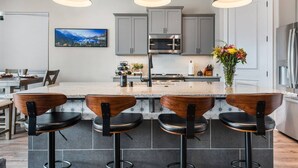 A modern kitchen with a central island, bar stools, and pendant lighting. - Grill and Chill by J and Amy BL 992912 (Mesquite)