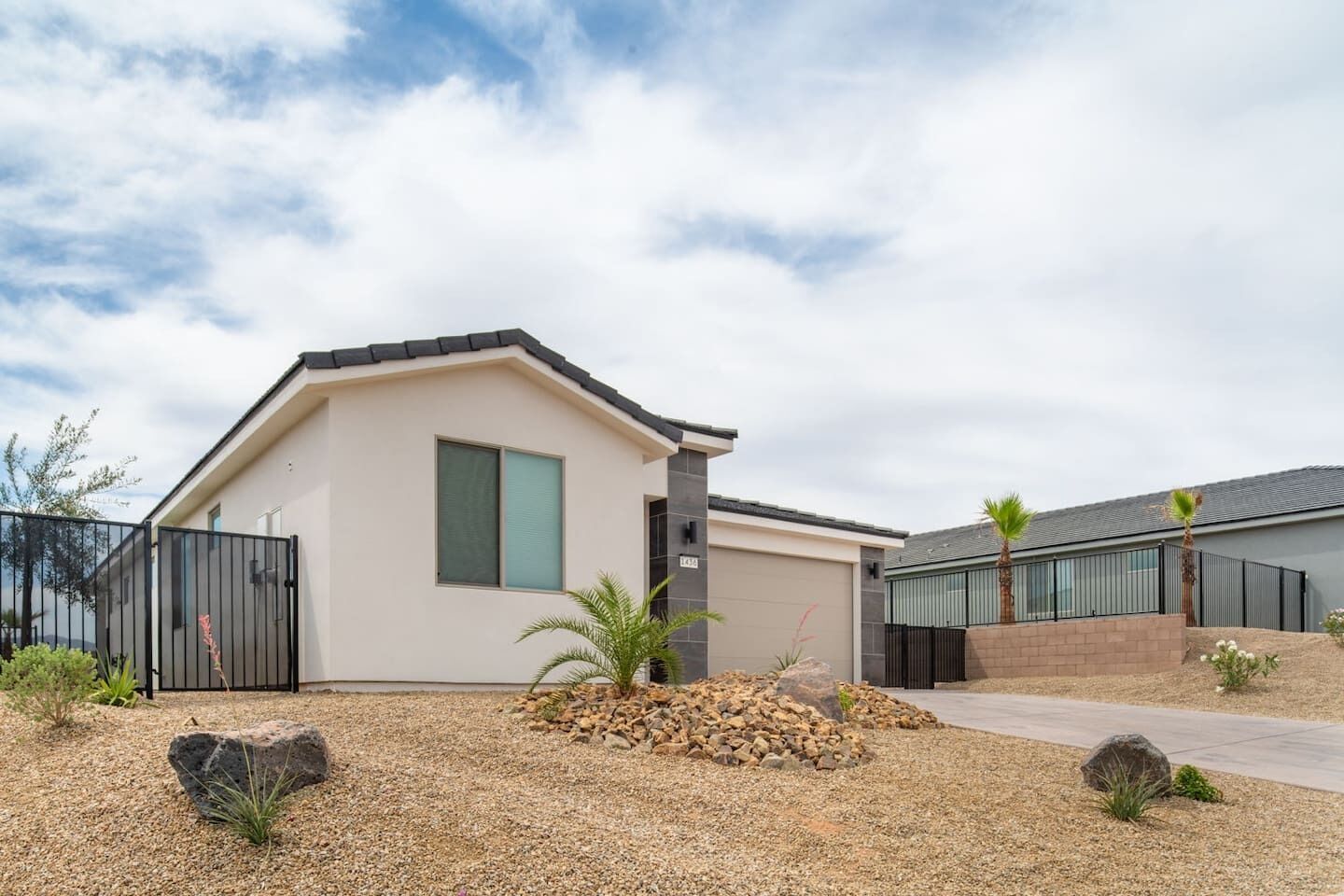 A modern two-story house with a flat roof, a large window, and a paved driveway.