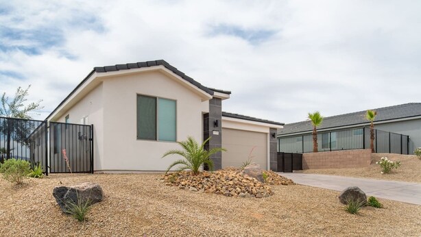 A modern two-story house with a flat roof, a large window, and a paved driveway. - Grill and Chill by J and Amy BL 992912 (Mesquite)