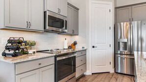 A modern kitchen with stainless steel appliances, a wine rack, and a white tiled backsplash. - Grill and Chill by J and Amy BL 992912 (Mesquite)