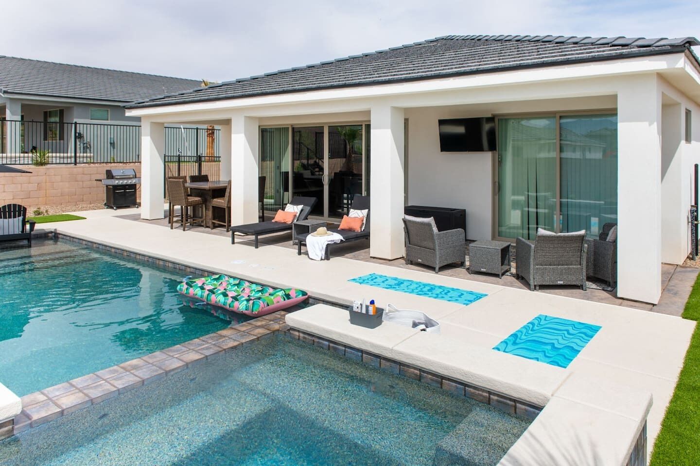 Una casa moderna con piscina, mobiliario exterior y zona de barbacoa.