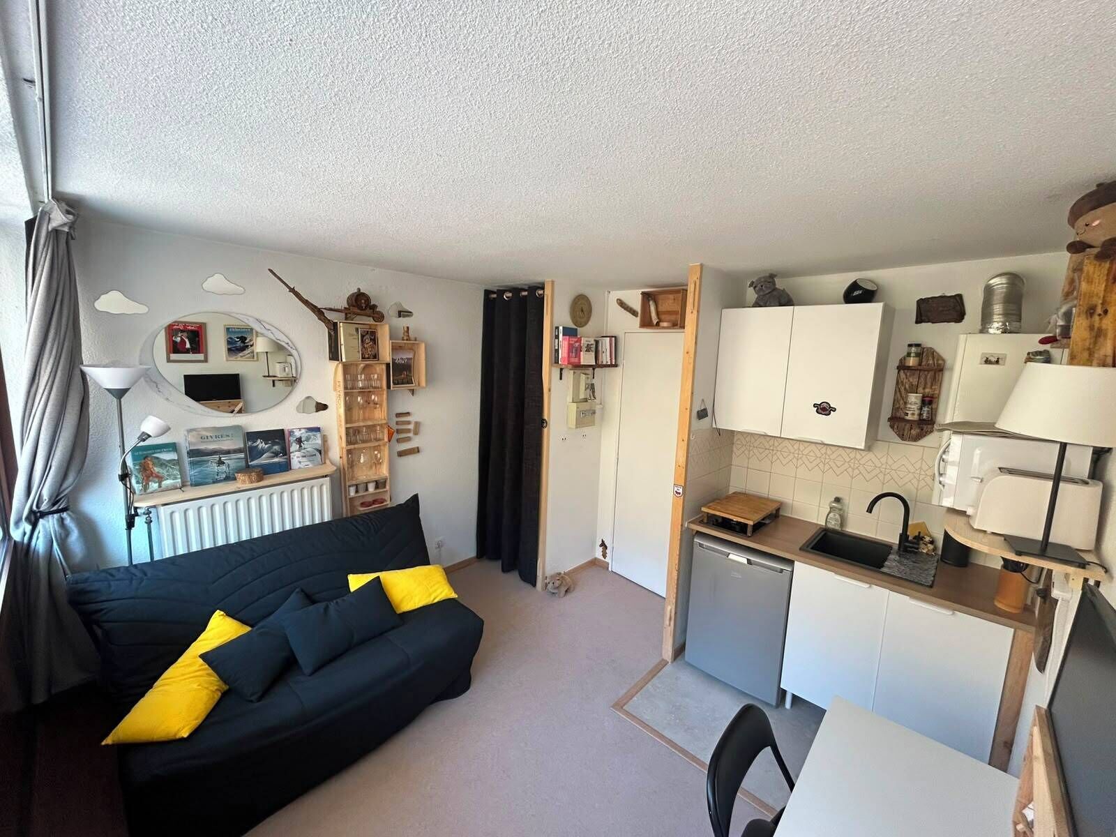 Un espace de vie compact comprenant un canapé, une petite kitchenette et un coin repas.