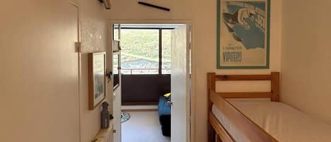 A narrow room with bunk beds, a radiator, a framed picture, and a poster on the wall.