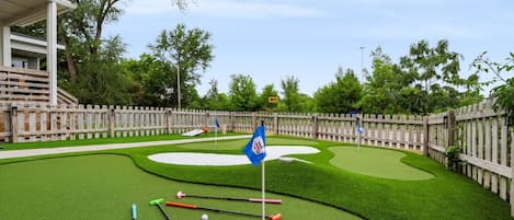 Un campo de mini golf con una valla de madera, una bandera y palos de golf.