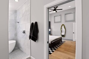 Een moderne badkamer met douche, toilet en handdoekhouder.