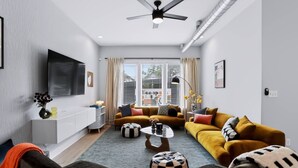 En moderne stue med sofasæt, sofabord og fjernsyn ophængt på væggen.
