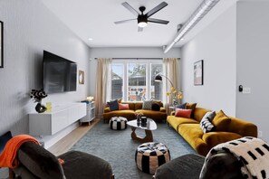 Ein modernes Wohnzimmer mit einer Sofagarnitur, einem Couchtisch und einem an der Wand befestigten Fernseher.