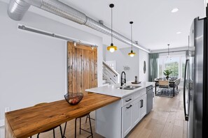Een moderne keuken met een houten bar, roestvrijstalen apparatuur en hanglampen.