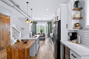 A modern kitchen with a central island, stainless steel appliances, and a view to the dining area. - 5 min to Lucas Oil-3 hole mini putt course-Hottub (Indianapolis)