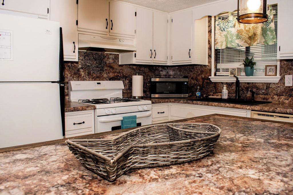 A kitchen with white cabinets, a gas stove, a microwave, and a granite countertop.