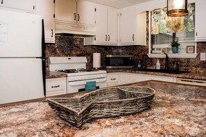 A kitchen with white cabinets, a gas stove, a microwave, and a granite countertop. - Cozy 2-bedroom condo with AC in welcoming Panama City Beach (Panama City Beach)