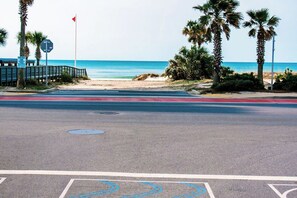 A beachside road with a pedestrian path, palm trees, and a clear view of the ocean. - Cozy 2-bedroom condo with AC in welcoming Panama City Beach (Panama City Beach)