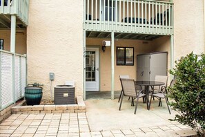 A patio area with a table and chairs, a trash can, and a utility box. - Cozy 2-bedroom condo with AC in welcoming Panama City Beach (Panama City Beach)