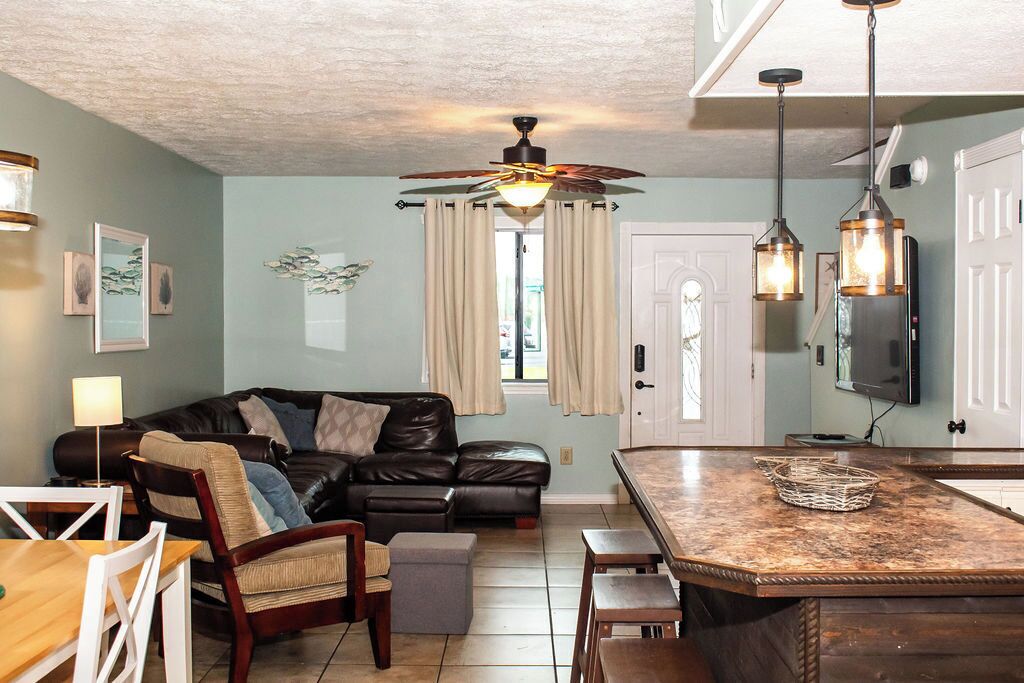 A living room with a leather sofa, a dining table, and a kitchen area with a marble countertop.