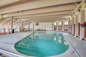 An indoor swimming pool with a clear water surface, surrounded by lounge chairs and a wooden ceiling structure. - Waterville Estates Condo- Hot Tub- Pools- Ski Mtn (Campton)