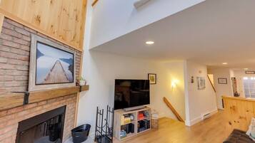 Een moderne woonkamer met een open haard, een flatscreen televisie en een houten trap.