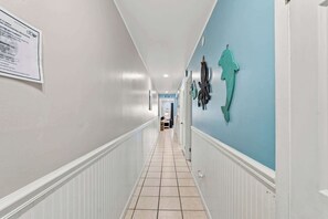 A hallway with white walls, a blue accent wall, and a tiled floor. - The Summit 308 - Best of PCB with Beach Service (Panama City Beach)