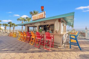 Un bar tiki con asientos al aire libre y vista al océano.