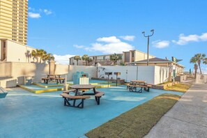 An outdoor patio area with picnic tables and a swimming pool. - The Summit 308 - Best of PCB with Beach Service (Panama City Beach)