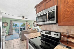 A kitchen with a microwave, stove, and cabinets. - The Summit 225 - Ocean Views & Beach Vibes (Panama City Beach)