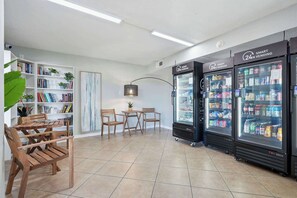 A modern interior with a seating area, a bookshelf, and two 24-hour vending machines. - The Summit 225 - Ocean Views & Beach Vibes (Panama City Beach)