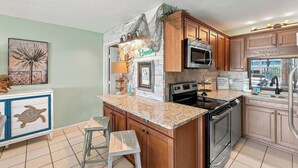 A kitchen with wooden cabinets, a granite countertop, a stainless steel oven, and a microwave. - The Summit 225 - Ocean Views & Beach Vibes (Panama City Beach)