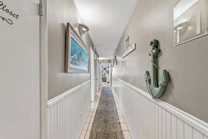 A hallway with white wainscoting, a patterned rug, and a green anchor decoration on the wall. - The Summit 225 - Ocean Views & Beach Vibes (Panama City Beach)