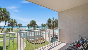 A balcony with a view of a pool, palm trees, and a beach. - The Summit 225 - Ocean Views & Beach Vibes (Panama City Beach)