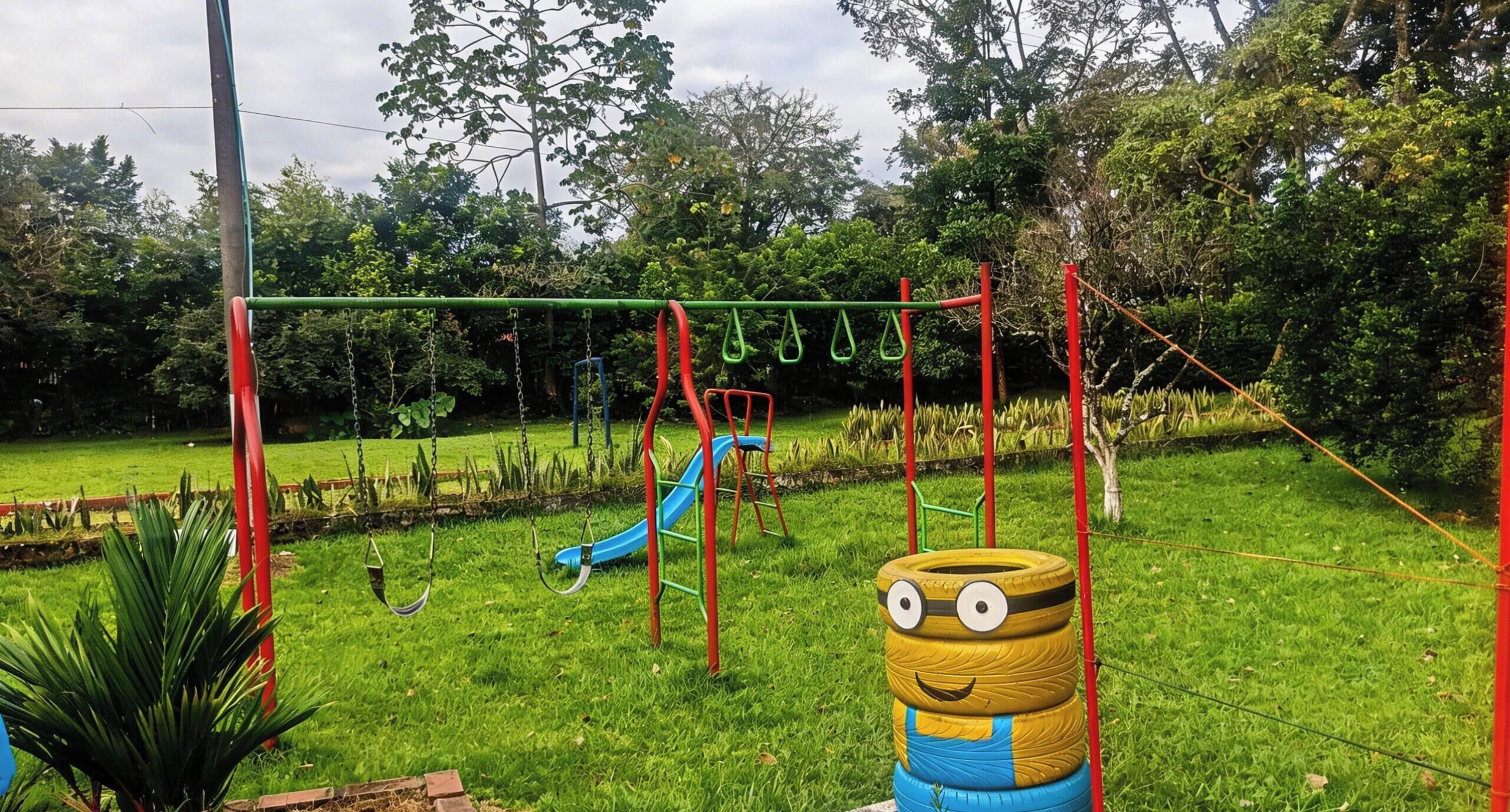 Un parque infantil con columpios, tobogán y una escultura hecha con neumáticos.