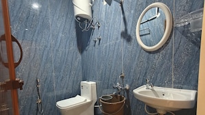A bathroom with a toilet, sink, and shower. - Hotel Udupi Palace (Mysore)