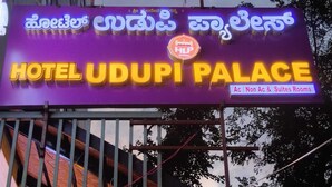A hotel sign with 'HOTEL UDUPI PALACE' and 'Ac | Non Ac & Suites Rooms' indicating accommodation types. - Hotel Udupi Palace (Mysore)