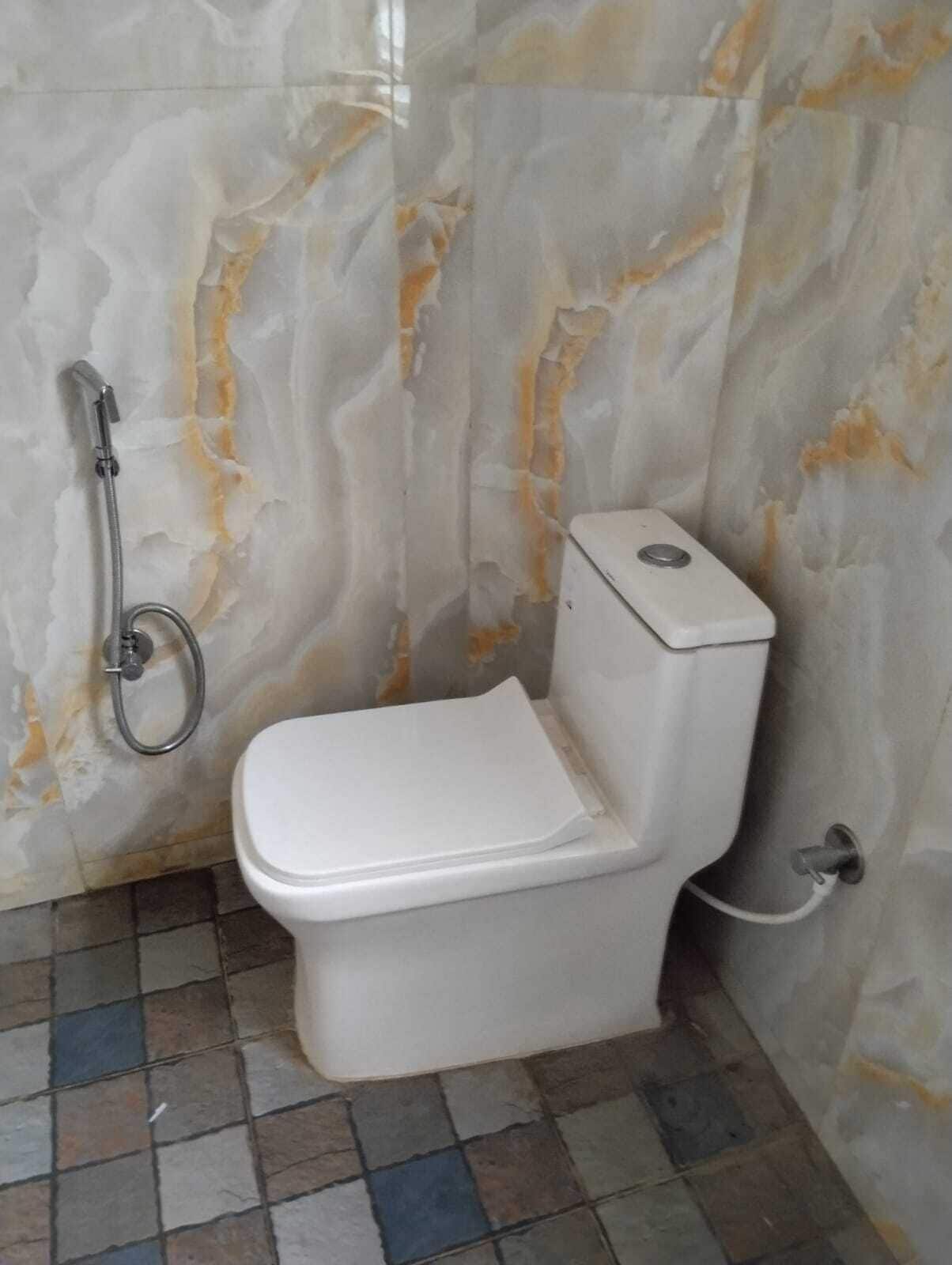 Un baño con inodoro, ducha y pared de mármol.
