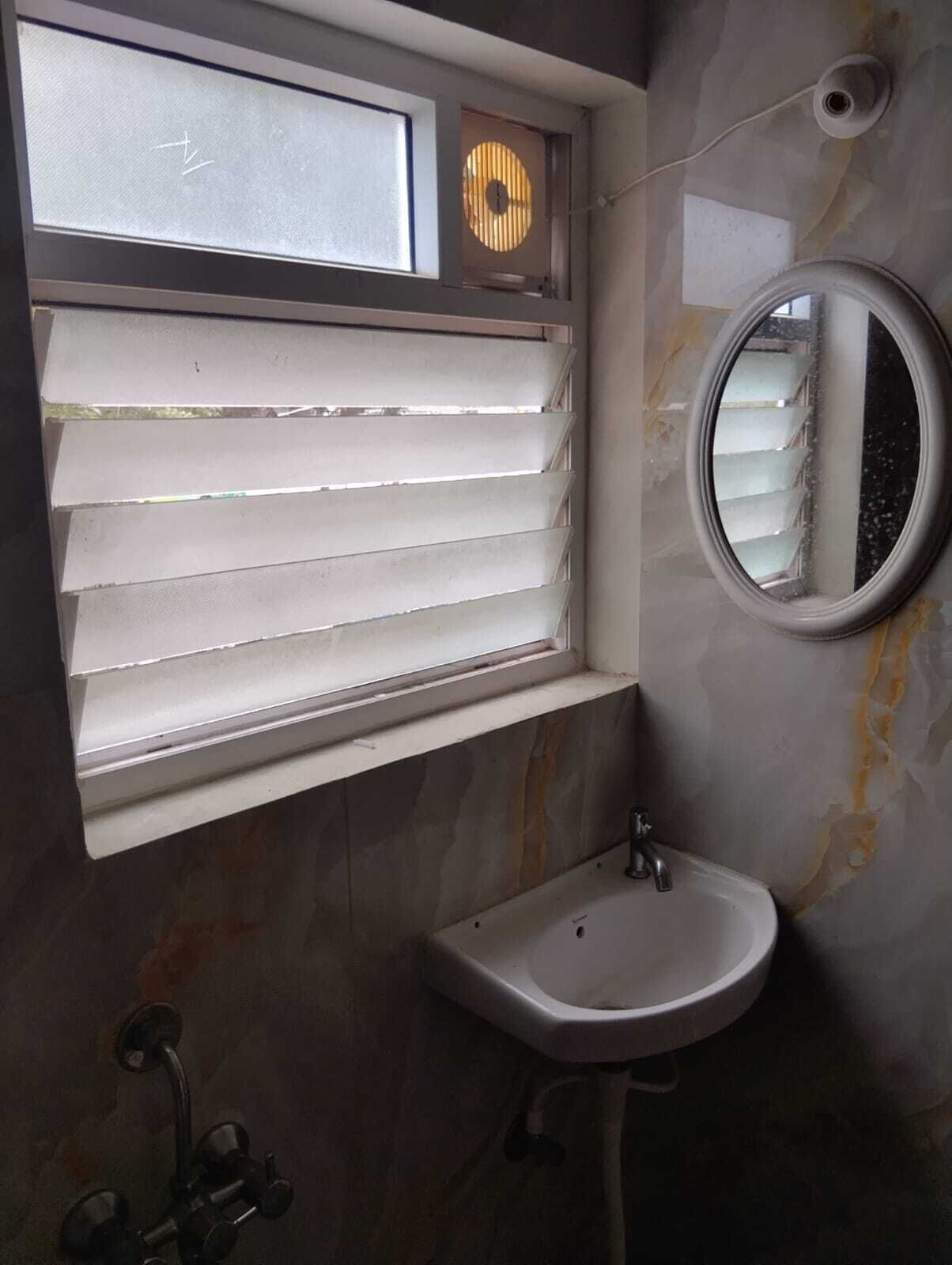 A bathroom with a window, a sink, and a mirror.